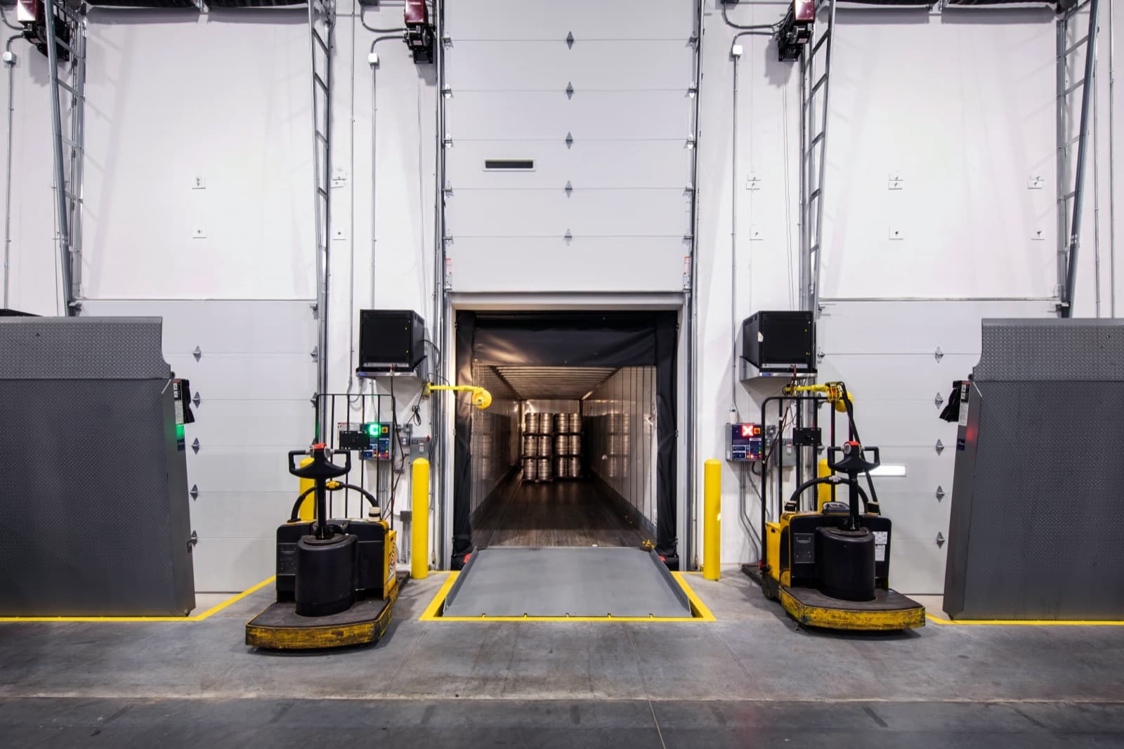 Distribution center loading dock with an open trailer, dock plate and pallet jacks